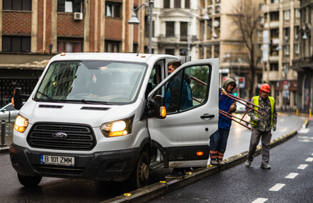 Workers unloading pieces of scaffold on a rainy day on the Victoriei boulevard in Bucharest city, Romania 2020のeditorial素材