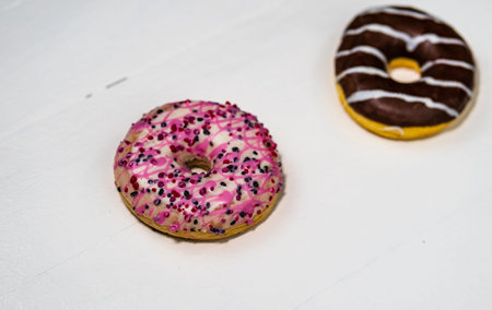 Colorful donuts on white wooden table. Sweet icing sugar food with glazed sprinkles, doughnut with...
