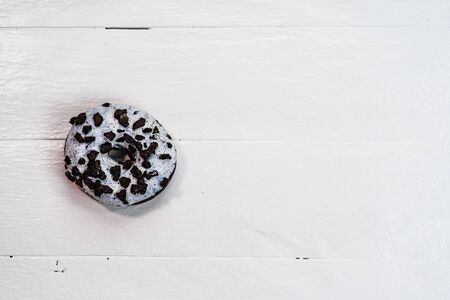Colorful donuts on white wooden table. Sweet icing sugar food with glazed sprinkles, doughnut with frosting. Top view with copy spaceの写真素材