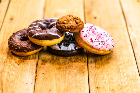 Colorful donuts on wooden table. Sweet icing sugar food with glazed sprinkles, doughnut with...