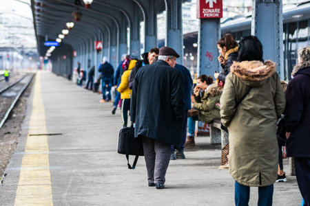 Travelers and commuters carry luggage and backpacks on the train platform of Bucharest North Railway...
