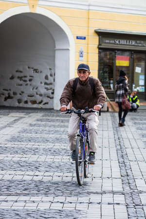 Old man riding a bike in downtown of Sibiu, Romana, 2020.のeditorial素材