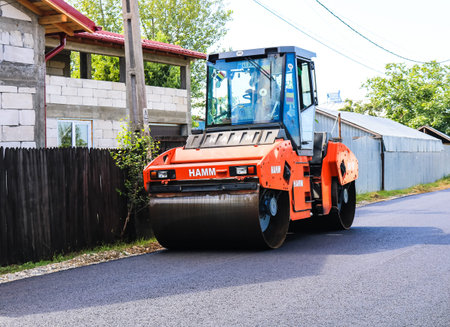 Workers and asphalting machines. Heavy road roller in motion on the roadway. Construction of a new...