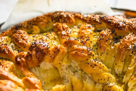 Close up photo with selective focus on details of salt and poppy seeds over a braided puff pastry.