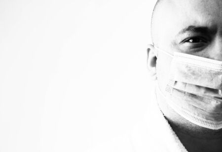 BW portrait of young man with medical face mask that illustrates pandemic coronavirus, Covid 19 disease isolated on white. Covid-19 outbreak, flu contamination and healthcare conceptの写真素材
