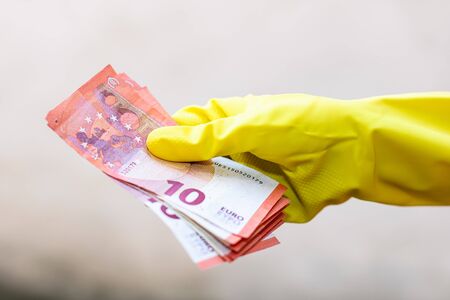 World money concept, hand with gloves receiving, giving or holding 10 EURO banknote, isolated on blurred background. Corona virus COVID-19 outbreak. Concept of prevention virus spreadの写真素材