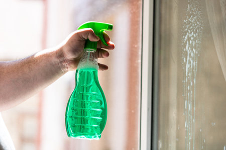 Man cleaning window using window cleaning squeegee and cleaning sprayer, cleaning services concept....