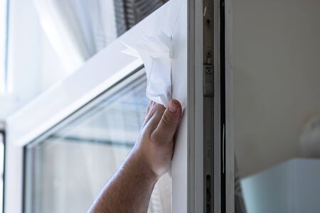 Man wiping window using paper towels, cleaning services concept. Housework and housekeeping conceptの写真素材