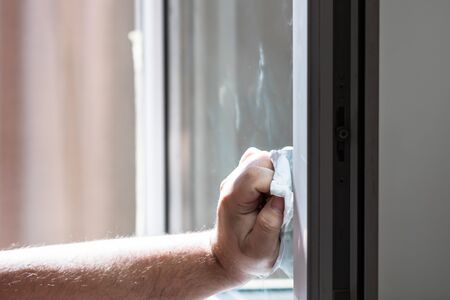 Man wiping window using paper towels, cleaning services concept. Housework and housekeeping conceptの写真素材