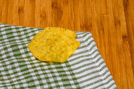 Detail of crispy potato chips on napkin on wooden table. Salted potato chips, junk food conceptの写真素材