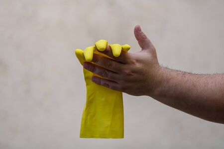 Hand holding yellow rubber glove on a blurred background. Recycle and volunteer concept. Environmental pollution and worldwide ecological problemの写真素材