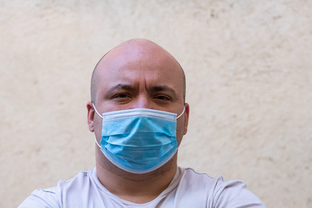 Caucasian young man with medical protective face mask illustrates pandemic coronavirus, Covid 19...
