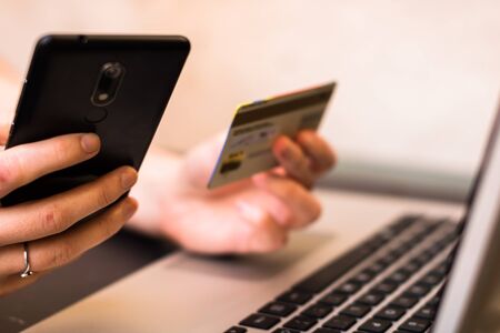 Selective focus of hands holding credit card and using smartphone and laptop. Online shopping, on line payment conceptの写真素材