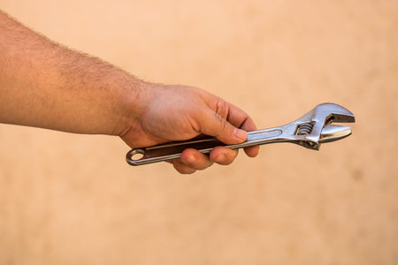 Tools for repair and building. Hand holding an adjustable spanner on blurred background