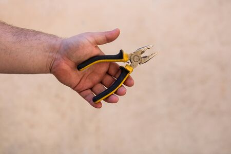 Tools for repair and building. Hand holding pliers on blurred backgroundの写真素材