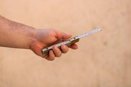 Tools for repair and building. Hand holding a ruler on blurred backgroundの写真素材