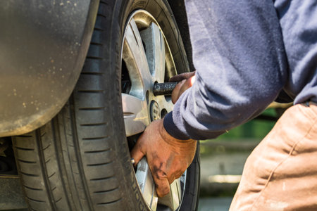 Car mechanic screwing or unscrewing car wheel by wrench at car garage in Bucharest, Romania, 2020