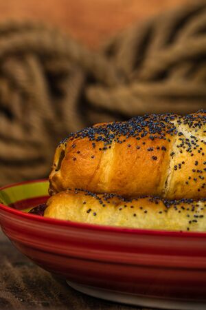 Sausages baked in dough sprinkled with salt and poppy seeds in a rustic composition. Sausages rolls, delicious homemade pastries.の写真素材