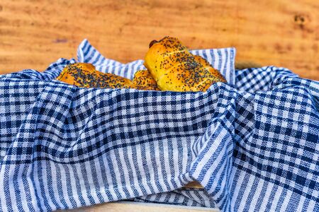 Sausages baked in dough sprinkled with salt and poppy seeds in a rustic basket. Sausages rolls, delicious homemade pastries in a rustic composition.の写真素材