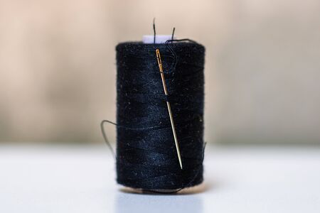 Black spool of sewing threads isolated on blurred background.の写真素材
