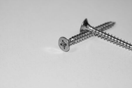 Close up photo of screws, set of screws in a construction abstraction. Industrial background with screws on a white boardの写真素材