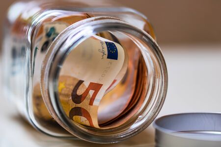 Composition with saving money banknotes in a glass jar. Concept of investing and keeping money, close up isolated.の写真素材