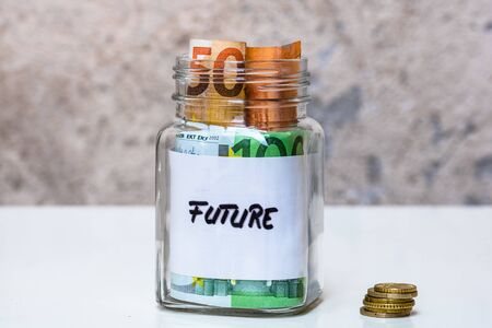 Composition with saving money banknotes in a glass jar with text future. Concept of investing and keeping money, close up isolated.の写真素材