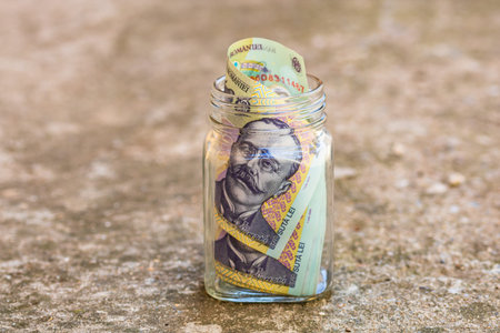 Composition with saving money romanian LEI banknotes in a glass jar. Concept of investing and...