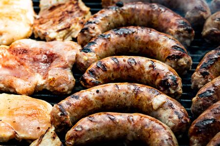 Close up on details of homemade chicken, pork steak and sausages on barbecue grill. Barbecue, grill and food concept.の写真素材
