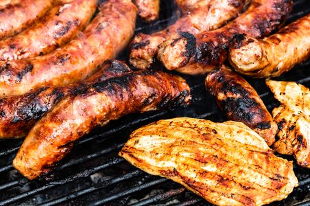 Close up on details of homemade chicken, pork steak and sausages on barbecue grill. Barbecue, grill and food concept.の写真素材