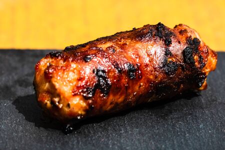 Close up of grilled sausage on small black cutting board isolated. Barbecue, grill and food concept.の写真素材