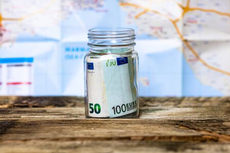 Composition with saving money banknotes in a glass jar. Concept of investing and keeping money for dreams and travel, close up isolated.の写真素材