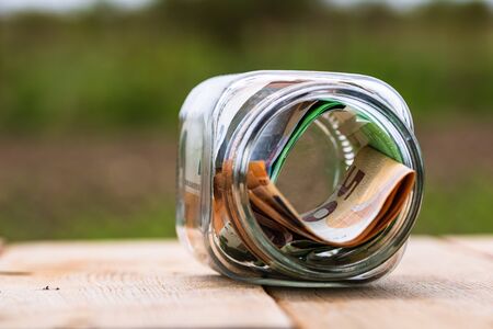 Composition with saving money banknotes in a glass jar. Concept of investing and keeping money, close up isolated.の写真素材