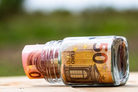 Composition with saving money banknotes in a glass jar. Concept of investing and keeping money, close up isolated.の写真素材