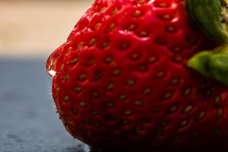 Close up of fresh strawberry showing seeds achenes. Water drop on fresh ripe red strawberry.の写真素材