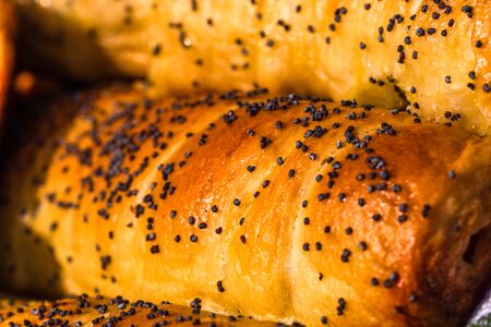 Close up on details of sausages baked in dough sprinkled with salt and poppy seeds. Sausages rolls, delicious homemade pastries.の写真素材