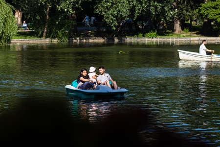 People on pedal boat on lake in Cismigiu Park, Bucharest, Romania, 2020. People walking, having fun, enjoying outdoor in park after quarantine or restrictions of coronavirus.のeditorial素材
