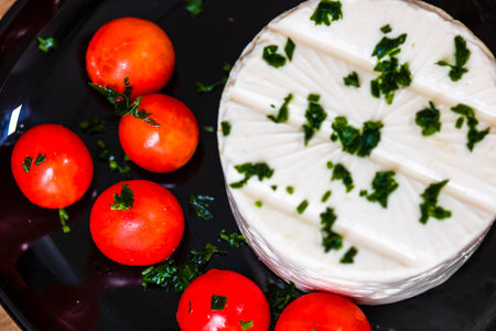 Breakfast food, cheese and cherry tomatoes on dish, on a rustic wooden plank board table background.