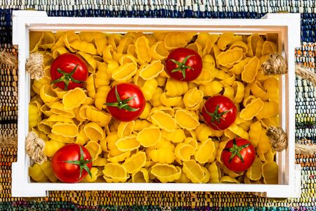 Gnocchi, raw italian pasta and cherry tomatoes in a wooden crate in a rustic composition.の写真素材
