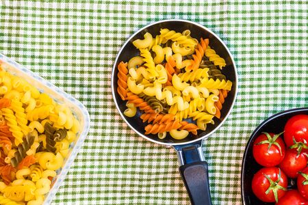 Small mini frying pan with tricolor raw fusilli pasta in a rustic composition.の写真素材