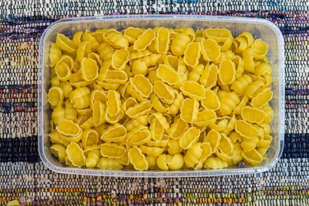 Gnocchi raw Italian pasta in plastic container, close up isolated in rustic compositionの写真素材