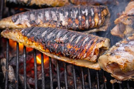 Grilled fish with smoke on a charcoal barbecue. Close up fish on the grillの写真素材