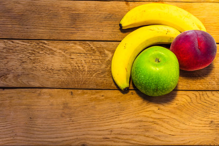 Apple, peach and bananas on a wooden board. Composition of healty fruits.