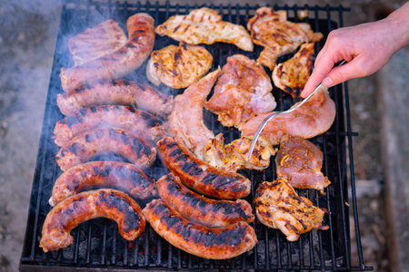 Preparing pork meat and sausages grilled on a charcoal barbeque. Top view of tasty barbecue, food...