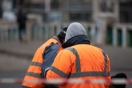 Back view of construction worker wearing dirty reflective jacket preparing for work. Bucharest,...