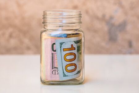 Composition with saving money banknotes in a glass jar. Concept of investing and keeping money, close up isolated.の写真素材