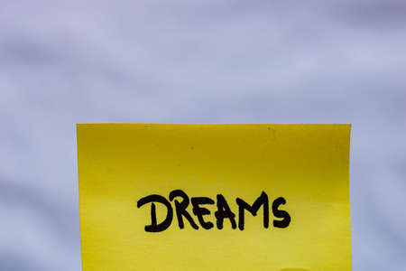Dreams  handwriting text close up isolated on yellow paper with copy space.の写真素材