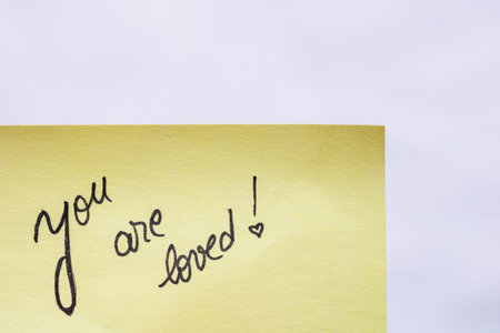 You are loved handwriting text close up isolated on yellow paper with copy space.