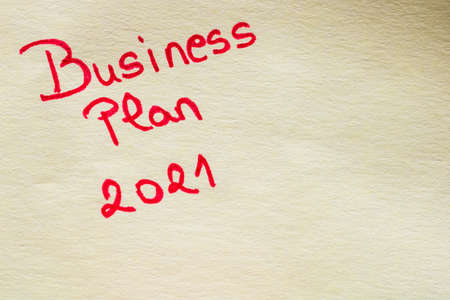 Business plan 2021 handwriting text close up isolated on yellow paper with copy space.の写真素材