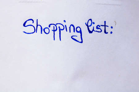 Shopping list handwriting text close up isolated on white paper with copy space. Writing text on memo post reminderの写真素材